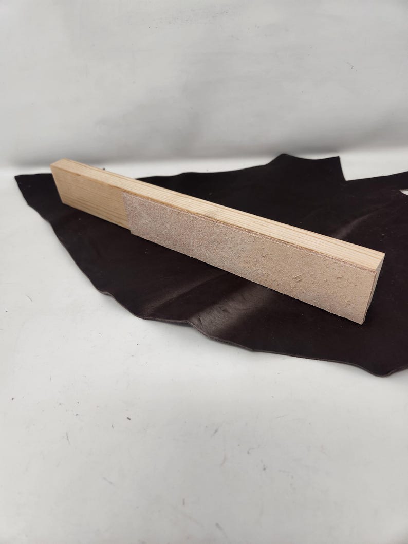 May include: A wooden sanding block with a rough surface. The block is light brown and has a rectangular shape.