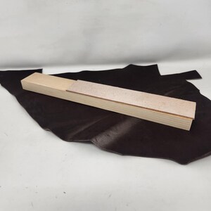 May include: A wooden sanding block with a light brown sanding surface. The block is open and the sanding surface is visible.