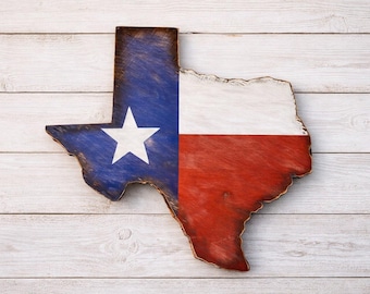 May include: Wooden Texas state cutout painted with the Texas flag. The blue section features a white star, while the other half is red and white. The cutout is placed on a white wooden plank background.