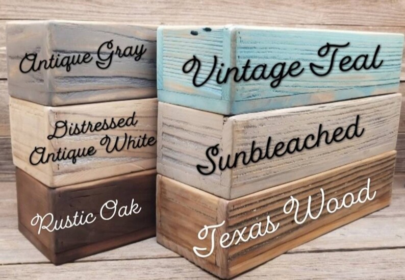 May include: Stacked wooden blocks painted in various colors and distressed finishes. The blocks are labeled with the paint colors: Antique Gray, Distressed Antique White, Rustic Oak, Vintage Teal, Sunbleached, and Texas Wood.