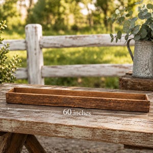 May include: A long, rectangular wooden trough with a dark brown, weathered finish. The item is positioned horizontally and features a clear label indicating a length of 60 inches. The structure is open at the top with four straight sides.