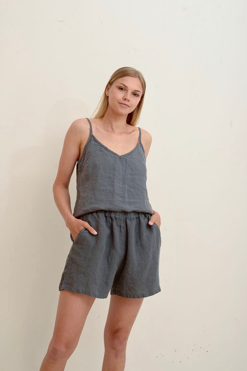 Puede incluir: Una mujer con un top de tirantes de lino gris y pantalones cortos de lino a juego. Los pantalones cortos tienen una cintura el&aacute;stica y bolsillos.