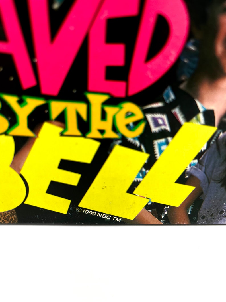 May include: A black and yellow poster with the words "Saved by the Bell" in large, colorful letters. The poster also includes the copyright information "&copy; 1990 NBC TM".