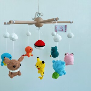 May include: A wooden baby mobile with crocheted Pokemon characters, including Pikachu, Bulbasaur, Charmander, Squirtle, and a Pokeball. The mobile also features white crocheted clouds.