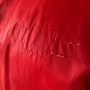 May include: A trio of cream-glazed ceramic mugs with a speckled finish. Each mug is adorned with a hand-painted design: a blue and green leaf, a yellow flower, and a red berry. The mugs have a simple, rounded form.