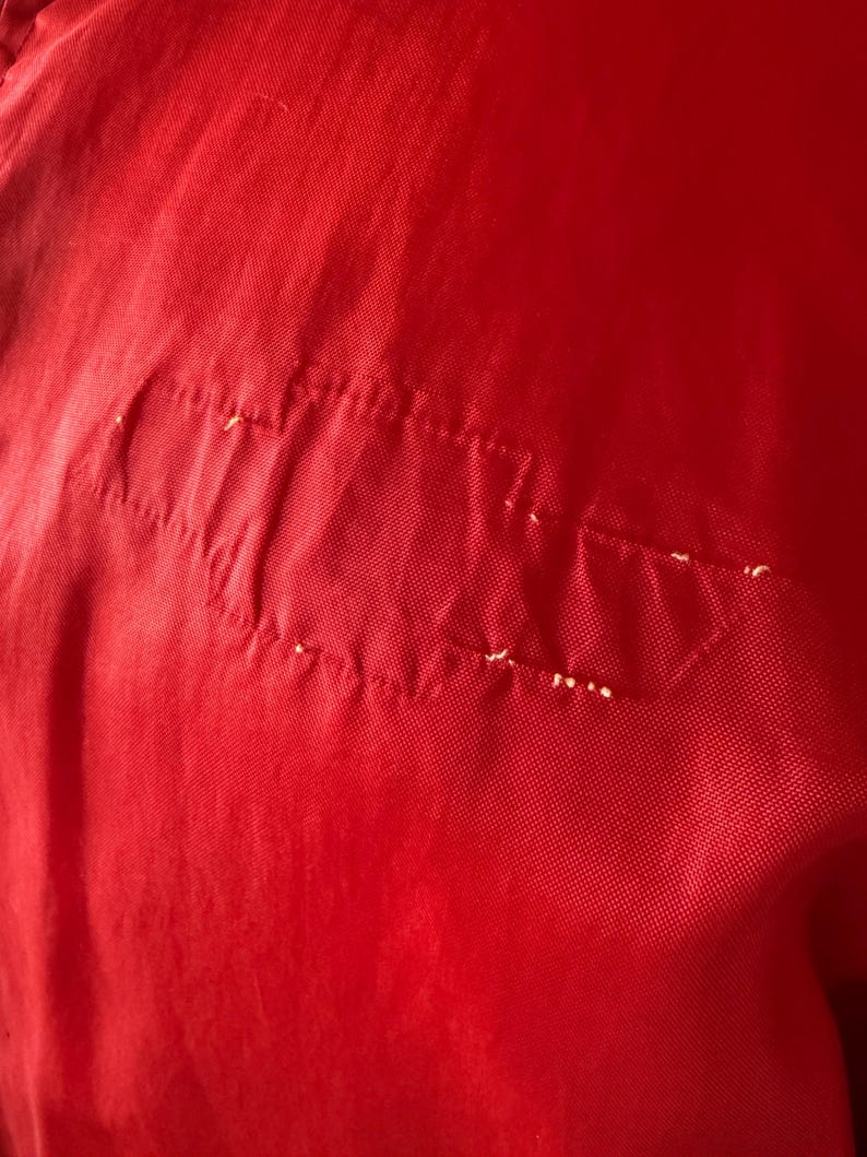 May include: A trio of cream-glazed ceramic mugs with a speckled finish. Each mug is adorned with a hand-painted design: a blue and green leaf, a yellow flower, and a red berry. The mugs have a simple, rounded form.