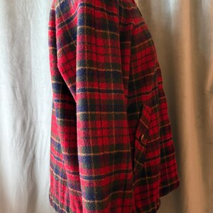 Puede incluir: Chaqueta a cuadros rojos, verdes, azules y dorados con cuello alzado. La chaqueta tiene cremallera frontal y dos bolsillos. Los pu&ntilde;os y el bajo son de punto azul oscuro.