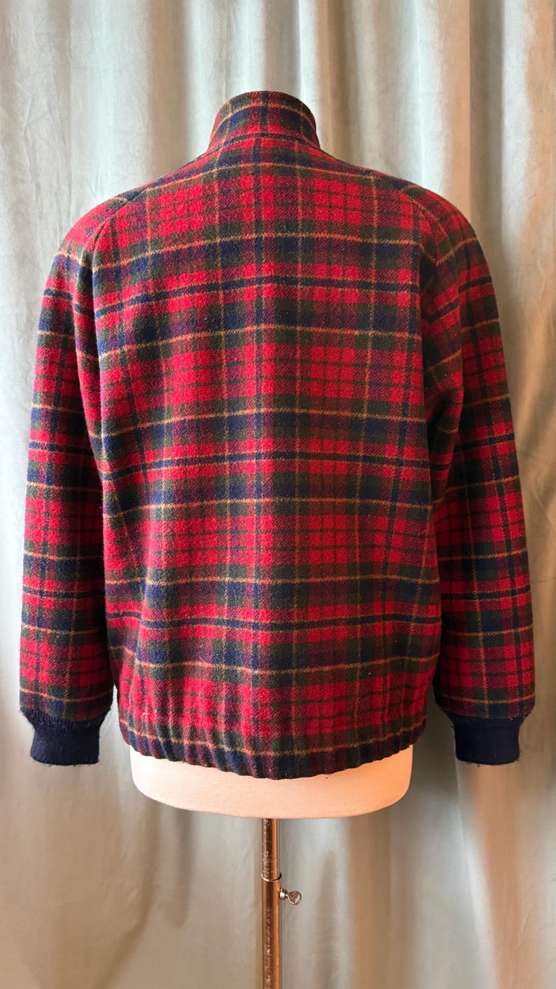 Puede incluir: Chaqueta a cuadros roja, verde y azul marino con cuello alto y pu&ntilde;os y dobladillo de canal&eacute; azul marino. La chaqueta se exhibe en un maniqu&iacute;.