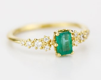 Anillo de compromiso con esmeralda talla esmeralda engastada en oro amarillo de 18 quilates y diamantes.