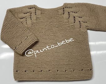 May include: A beige knitted sweater with a unique stitch pattern on the shoulders and sleeves. The sweater has a round neckline and long sleeves. The sweater is made of a soft, comfortable material.