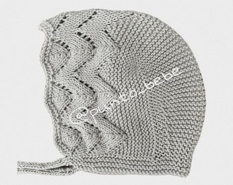 May include: A gray knitted baby bonnet with a cable knit pattern and a long tie. The bonnet has a delicate openwork design.