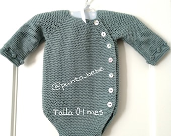 May include: A light blue knitted baby onesie with white buttons and the text "Talla 0+ mes" in white.
