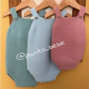 Puede incluir: Tres bodies de bebé de punto colgados de perchas de madera. Los bodies son de color azul claro, verde azulado y rosa. Los bodies tienen tirantes y cierre de botón. El texto '@punto_bebe' es visible en la imagen.