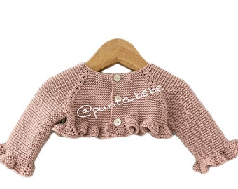 May include: A pink knitted baby cardigan with a ruffled hem and sleeves. The cardigan has a button closure in the back.