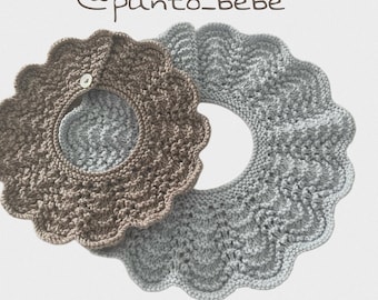 May include: Two knitted baby bibs with scalloped edges. One bib is light brown, the other is light gray. The bibs have a circular opening for the neck and a button closure. The text "@punto_bebe" is at the top.