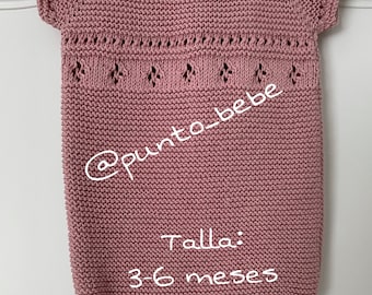 May include: A pink knitted baby onesie with short sleeves and a delicate lace pattern around the neckline. The onesie is labeled "Talla: 3-6 meses" which translates to "Size: 3-6 months".