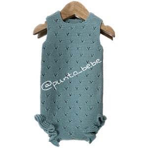 Könnte beinhalten: Ein hellblauer gestrickter Baby-Strampler mit einem zarten Lochmuster und Rüschenbesatz. Der Strampler hängt an einem Holzbügel. Der Text '@punto_bebe' ist auf dem Strampler sichtbar.