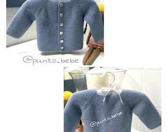 May include: A light blue knitted baby cardigan with a button closure. The cardigan is shown on a hanger and on a doll. The text '@punto_bebe' is visible on the image.