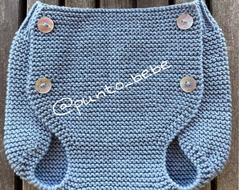 May include: A blue knitted baby diaper with four white buttons. The diaper is made with a simple stitch pattern.