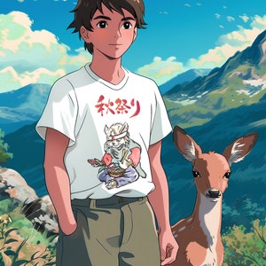 Puede incluir: Un joven con cabello casta&ntilde;o que lleva una camiseta blanca con un car&aacute;cter japon&eacute;s y una imagen de dibujos animados de un gato con una diadema y sosteniendo palillos. Est&aacute; de pie en un paisaje monta&ntilde;oso con un ciervo marr&oacute;n a su lado.