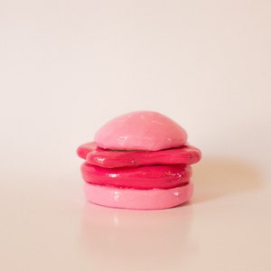 May include: A stack of four pink and red clay circles, resembling a miniature cake or a stack of cookies.