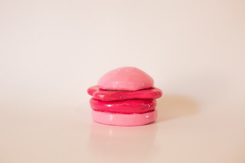 May include: A stack of four pink and red clay circles, resembling a miniature cake or a stack of cookies.