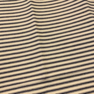 May include: A close-up of a cream-colored fabric with thin black stripes. The fabric is wrinkled and has a textured surface.