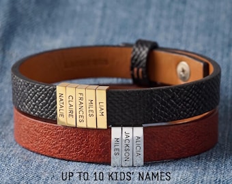 May include: Two stacked leather bracelets featuring metallic rectangular beads engraved with names. The top black bracelet has five gold-toned beads with the names NATALIE, CLAIRE, FRANCES, MILES, and LIAM. The bottom brown bracelet has three silver-toned beads with the names MILES, JACKSON, and ALICIA.
