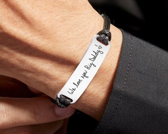 May include: A black leather bracelet with a silver rectangular tag engraved with the handwritten message "We love you Big Daddy!"