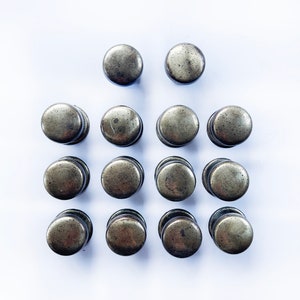 May include: A set of 14 antique gold-toned cabinet knobs. The knobs are round and have a slightly textured surface.