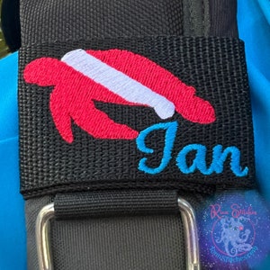 May include: A black fabric patch with a pink and white embroidered sea turtle and the name "Jan" in blue embroidery.