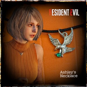 May include: A silver eagle pendant necklace with a green gemstone, worn by a woman with blonde hair. The necklace is labeled "Ashley's Necklace" and the background says "Resident Evil".