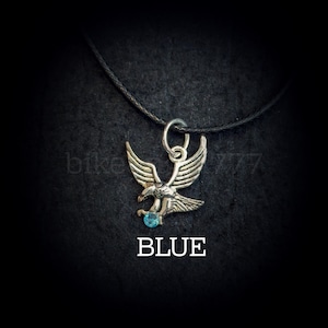 May include: Silver eagle pendant necklace with a blue gemstone. The necklace has a black cord.