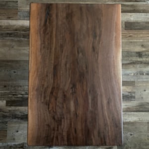 May include: A large, rectangular slab of dark brown wood with a natural wood grain pattern. The wood has a smooth, polished finish.