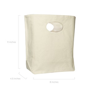 May include: A plain white canvas tote bag with a cut-out oval handle. The bag measures 11 inches tall, 8 inches wide, and 4.5 inches deep.