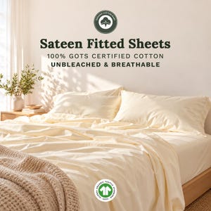 May include: Cream-colored sateen fitted sheets made of 100% GOTS certified cotton. The text reads: Organic Cotton Mart, Sateen Fitted Sheets, 100% GOTS Certified Cotton, Unbleached & Breathable. A GOTS Global Organic Textile Standard logo is visible.