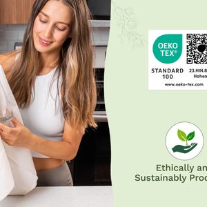 Op de afbeelding: Een vrouw houdt een witte doek en een glas vast. De afbeelding bevat een groen en wit Oeko-Tex Standard 100 label en een afbeelding met de tekst "Ethisch en duurzaam geproduceerd".