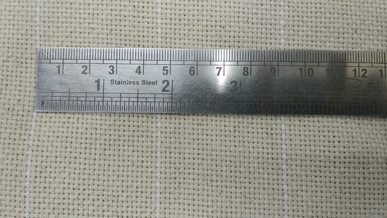 May include: A close-up of a silver metal ruler with inch markings. The ruler is labeled "Stainless Steel" and has markings up to 12 inches.