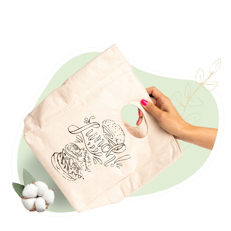 May include: A white canvas tote bag with black and white illustrations of sandwiches and the text "Lunch Time". The bag has a cut-out handle.