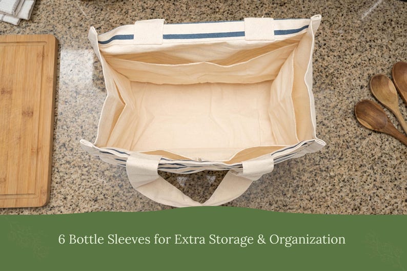 May include: An open rectangular canvas tote bag with cream-colored fabric and navy blue horizontal stripes. The interior features six internal bottle sleeves for organization. The text 6 Bottle Sleeves for Extra Storage & Organization is visible.