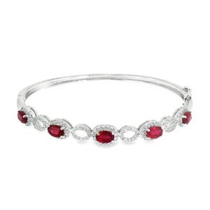 Puede incluir: Una pulsera rígida articulada de tono plateado con cinco rubíes rojos de corte ovalado en engastes individuales. Cada rubí está rodeado por un halo de pequeñas piedras blancas, con eslabones calados en forma de infinito uniendo los engastes.