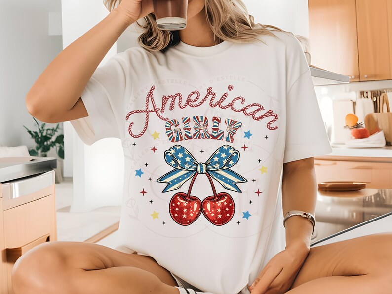 May include: White t-shirt featuring a red, white and blue cherry graphic and the text "American Girl" in a rope-like font.