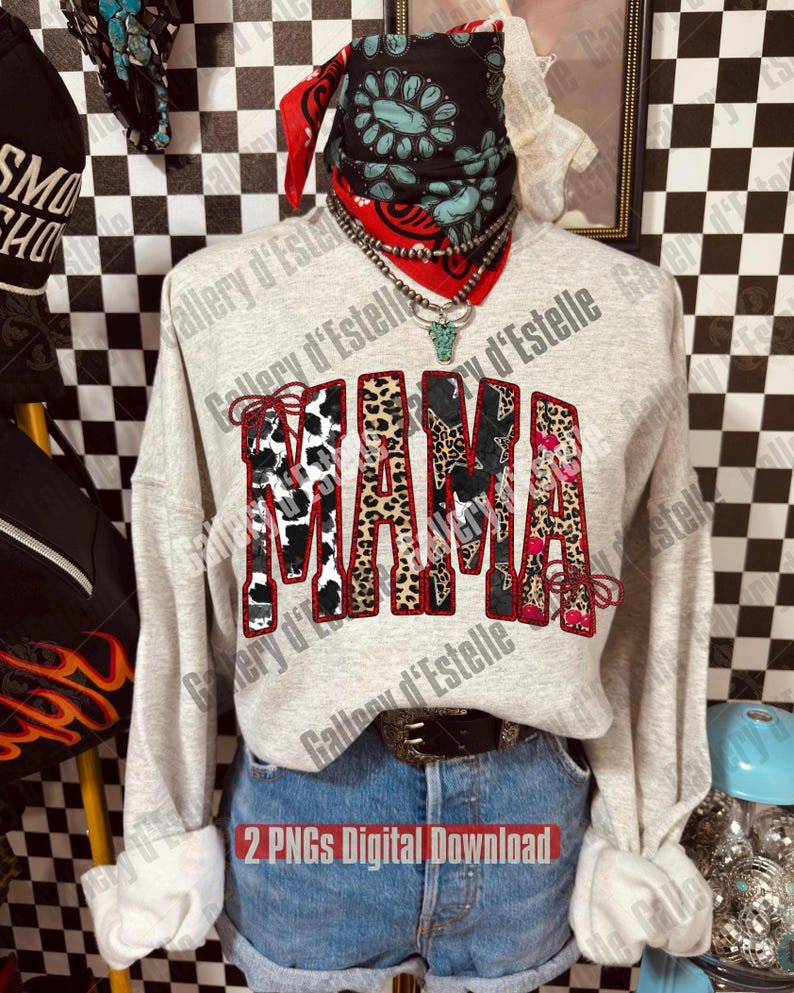 May include: A light gray sweatshirt with the word "MAMA" in a multi-patterned design. The letters feature cow print, leopard print, and floral patterns. The model is wearing denim shorts, a bandana, and jewelry.