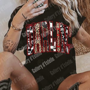 May include: Black t-shirt with the word "GALLERY" in a patchwork design featuring leopard print, cow print, stars, and stripes. The word is outlined in red. The shirt is part of a clothing collection.
