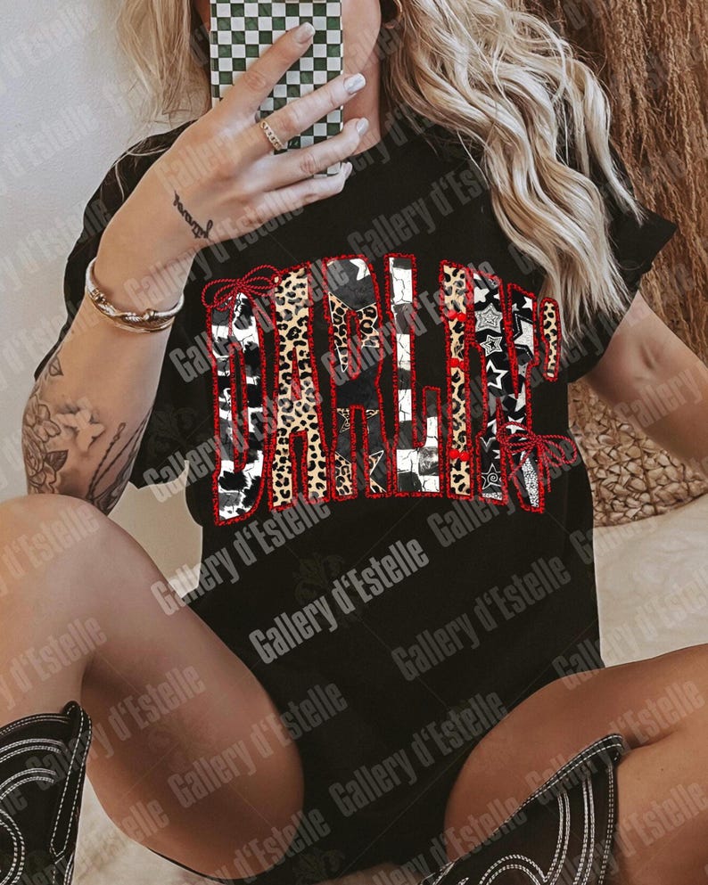 May include: Black t-shirt with the word "GALLERY" in a patchwork design featuring leopard print, cow print, stars, and stripes. The word is outlined in red. The shirt is part of a clothing collection.