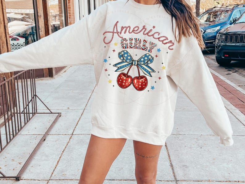May include: White sweatshirt with a red, white and blue graphic design that says "American Girl" with a cherry and bow design.