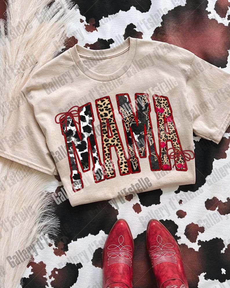 May include: A beige t-shirt with the word "MAMA" in a patchwork design featuring cow print, leopard print, and floral patterns. Red cowboy boots are at the bottom of the image, with a cowhide pattern in the background.