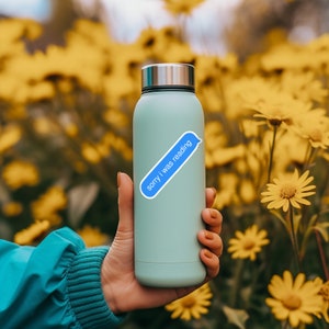 K&ouml;nnte beinhalten: Eine hellblaue wiederverwendbare Wasserflasche mit einem blauen Text-Aufkleber, auf dem "sorry i was reading" steht.