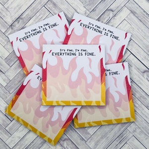 May include: A stack of five sticky notes with a flame design. The notes have the text "It's fine. I'm fine. Everything is fine." printed on them.