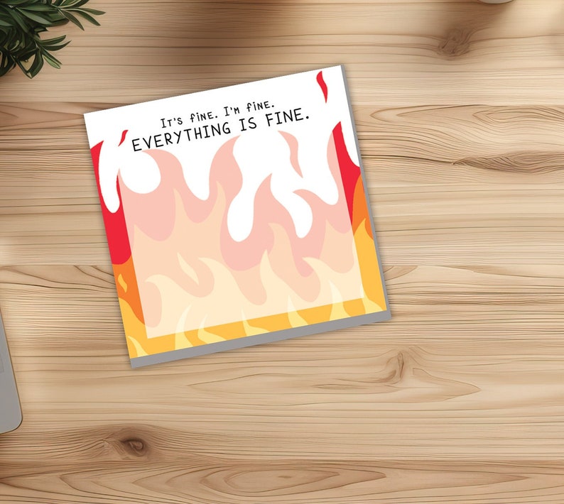 May include: A white card with red and yellow flames printed on it. The card has the text "It's fine. I'm fine. EVERYTHING IS FINE."